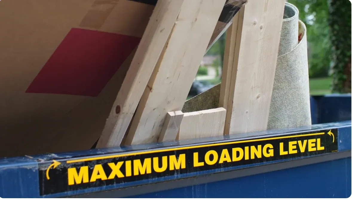 Roll-off dumpster filled with lumber and carpet below the maximum loading level line