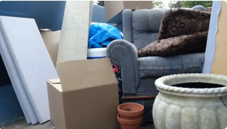 Household cleanout debris in a roll-off dumpster: armchair, boxes, cushions and planters